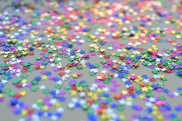 Festive colorful confetti scattered at the table. Close up of tiny shining stars.