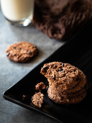 Chocolate cookies on grey table with a bottle of milk