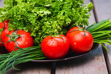 Fresh bright vegetables and herbs on a wooden table.