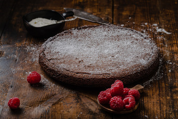 Chocolate mud cake, swedish kladdkaka or sticky chocolate cake with raspberries