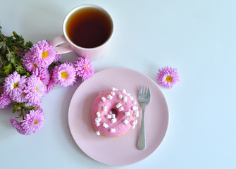 Obraz na płótnie Canvas pink teapot, cup of tea and colorful delicious doughnuts