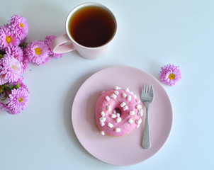 pink teapot, cup of tea and colorful delicious doughnuts