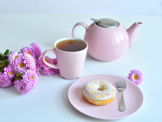pink teapot, cup of tea and colorful delicious doughnuts