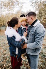 Family in a autumn park. Woman in a red dress. Cute child with parents