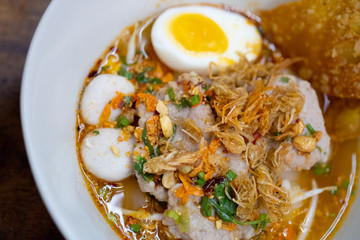 Spicy tom yum noodle with pork and meat ball and egg.