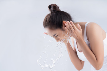 Beautiful woman washing her face in a white background studio