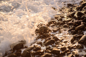 Volcanic pebbles on the ocean close up at sunset. The stones. Sea. Ocean.