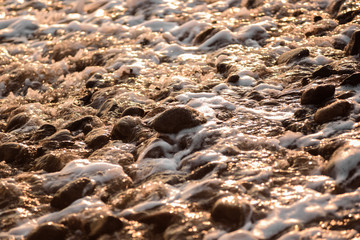 Volcanic pebbles on the ocean close up at sunset. The stones. Sea. Ocean.