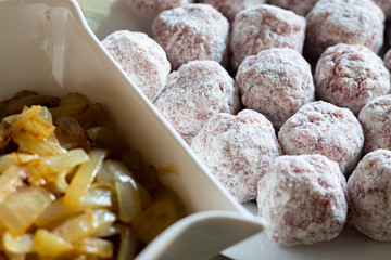 Homemade pork meat dumplings in onion sauce over white bowl