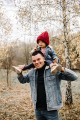 Family in a autumn park. Woman in a red dress. Cute child with parents