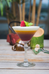 Tiramisu traditional dessert in a glass goblet on a wooden table.