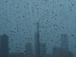 City skyline behind a rainy window, raindrops, gray rainy day