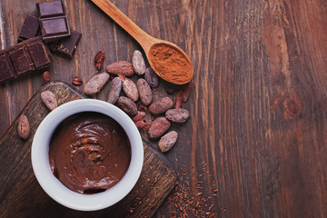 Chocolate cream, cocoa beans and powder and pieces of chocolate on the wooden table