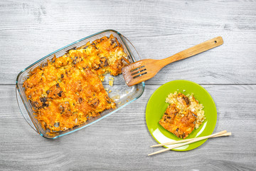 Salmon baked with potatoes under mayonnaise and cheese in a glass pan on a wooden table top view