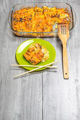 Salmon baked with potatoes under mayonnaise and cheese in a glass pan on a wooden table top view