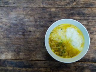 Rice porridge with pork and curry in Thai style on black wooden table.