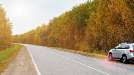 Brutal silver car stay on the roadside of an outdoor highway in autumn.