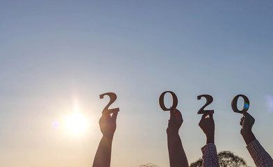 Hands holding 2020 numbers for new year at sunset background. the year of the white rat