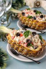 Festive salad with chicken in halves of pineapple on a light blue background, New Year, Valentine's Day, Romantic dinner, vertical orientation