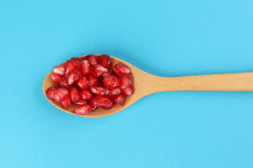 Red Pomegranate seed wooden spoon blue paper background