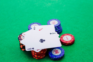 Cards with aces as a winning hand, on a stack of poker chips on a green table