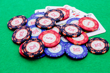 Lots of poker chips of different value on a winning hand of cards on a green table