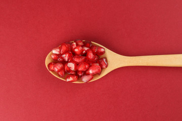 Red Pomegranate seed wooden spoon red paper background