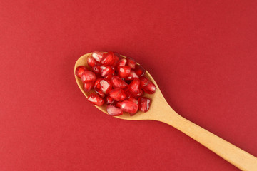 Red Pomegranate seed wooden spoon red paper background