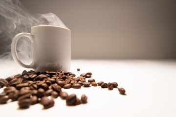 White coffee mug smoke coming out of the coffee cup. And coffee beans