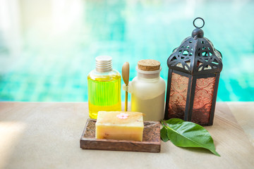 Spa concept background, Spa product body srub with herbal soap and vintage metal lamp over blurred swimming pool water background, outdoor day light