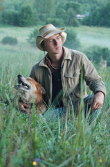 young handsome cowboy guy with dog on a walk in the evening