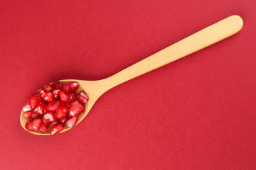Red Pomegranate seed wooden spoon red paper background
