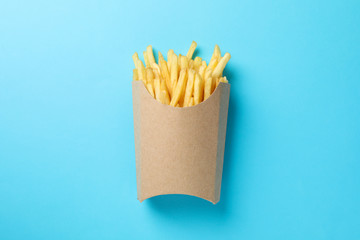 Slices of hot french fries in box on blue background, space for text. Top view