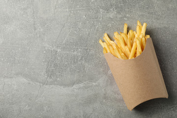 Slices of hot french fries in box on grey background, space for text. Top view