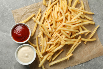 Tasty french fries, sauces on gray background, space for text. Top view