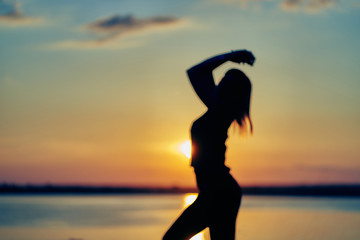 silhouette of a young woman at sunset. gymnastics, yoga, exercises, healthy lifestyle.