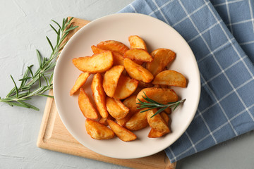 Plate with slices of baked potato wedges, napkin on gray background, space for text. Top view,...
