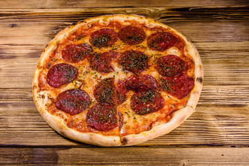 Pizza with salami sausage and parmesan cheese on a wooden table