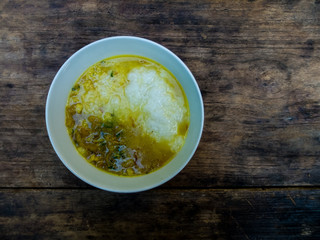 Rice porridge with pork and curry in Thai style on black wooden table.