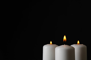 Glowing candles on black background, space for text