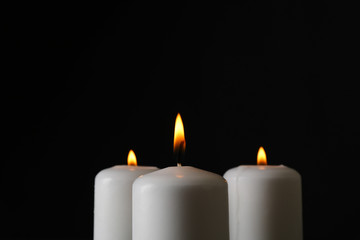 Glowing candles on black background, space for text