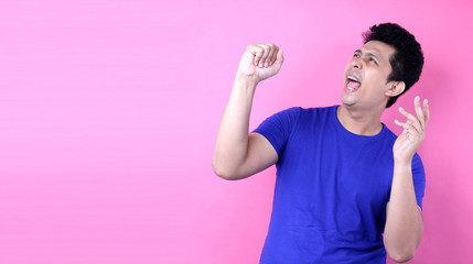 Portrait Handsome Asia man singing loud while standing  on pink background in studio With copy space.