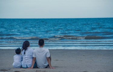 Family, parents, children, sitting on the beach by the sea on a vacation