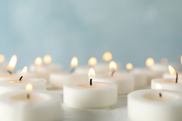 Group of burning candles against blue background, close up