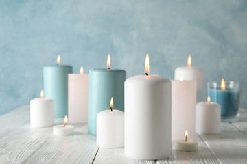Fototapeta na wymiar Different burning candles against blue background, space for text