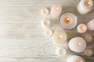 Different burning candles on wooden background, top view