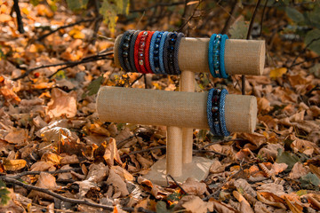 Obraz premium Beautiful, shiny, color bracelet with large beadwork beads. On a special stand for jewelry. Brown autumn foliage on the background.