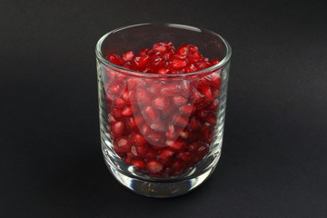 Red Pomegranate seed in glass on black paper background