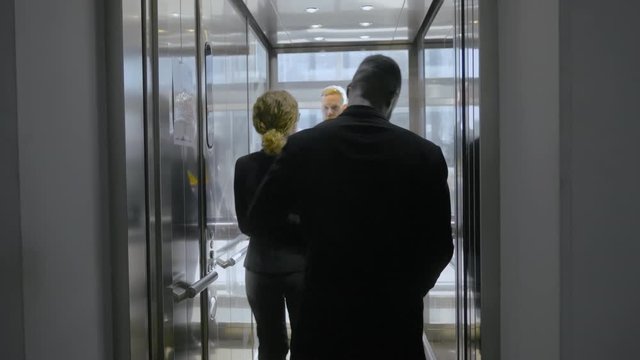 Office workers talking in elevator