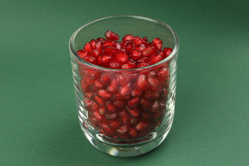 Red Pomegranate seed in glass on green paper background